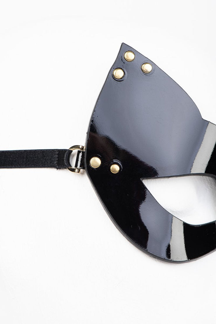 Black and gray cat-eye mask with gold studs on a white background
